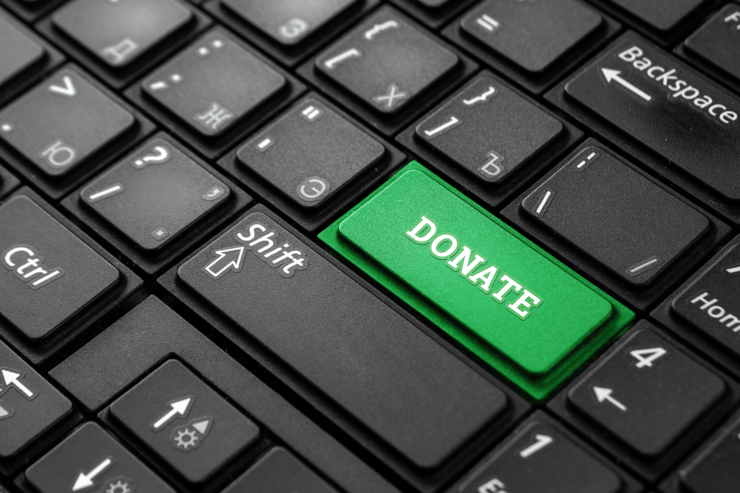 An image of a computer keyboard with a green donate button as one of the keys