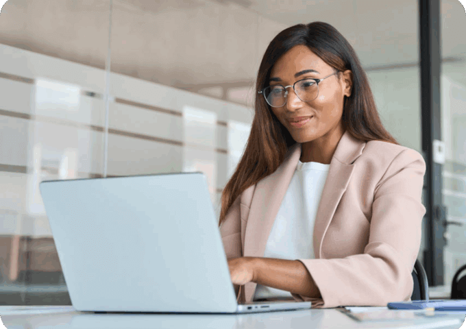 A woman sitting at a desk looking at a laptop